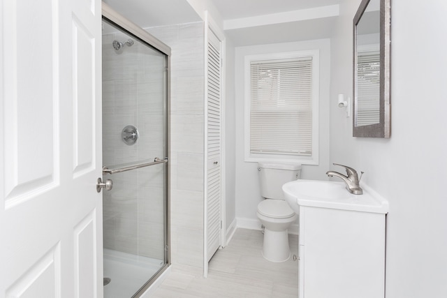 bathroom featuring a stall shower, toilet, baseboards, and a sink
