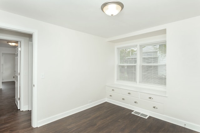 spare room with baseboards and dark wood finished floors