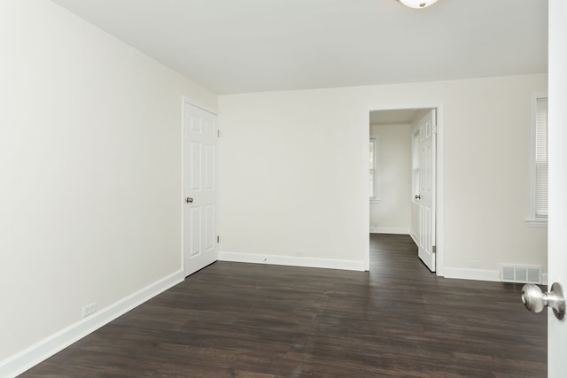 empty room with baseboards and dark wood-type flooring