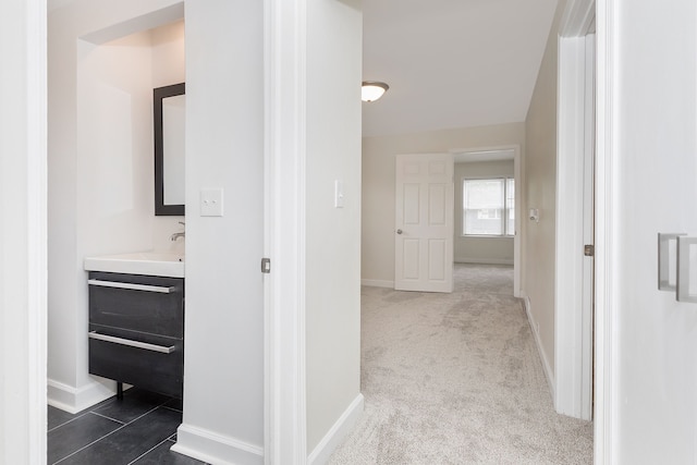 hall with dark colored carpet and baseboards