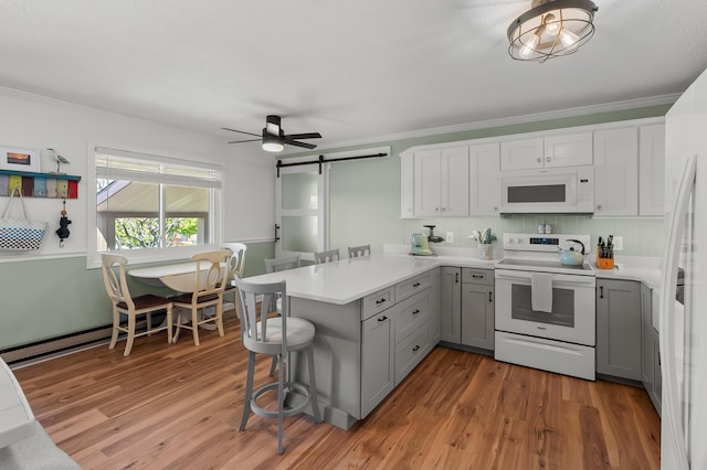 4150 Ridge Rd Unit 21And 22, Stevensville, MI 49127 - kitchen featuring white appliances, gray cabinets, a peninsula, a barn door, and wood finished floors