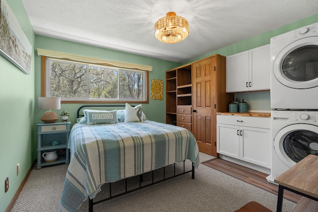 4150 Ridge Rd Unit 21And 22, Stevensville, MI 49127 - bedroom with stacked washer / drying machine, a textured ceiling, carpet, and a chandelier