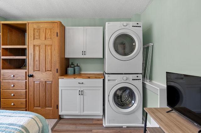 4150 Ridge Rd Unit 21And 22, Stevensville, MI 49127 - clothes washing area with stacked washer and clothes dryer, cabinet space, light wood-style floors, and a textured ceiling