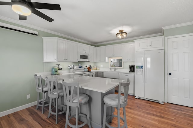 4150 Ridge Rd Unit 22, Stevensville, MI 49127 - kitchen featuring white appliances, a peninsula, ornamental molding, a kitchen bar, and white cabinetry