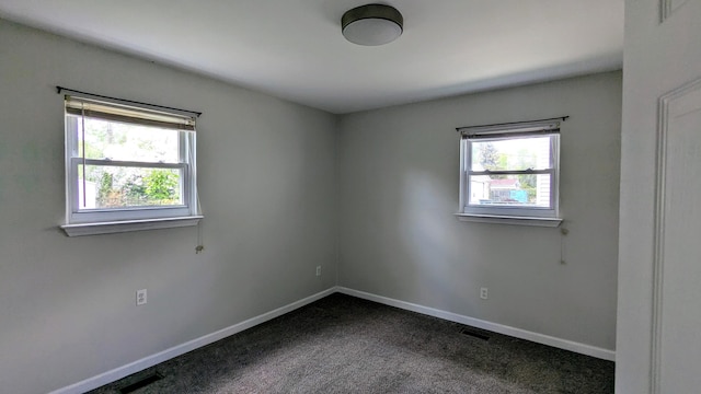 unfurnished room featuring dark colored carpet and baseboards
