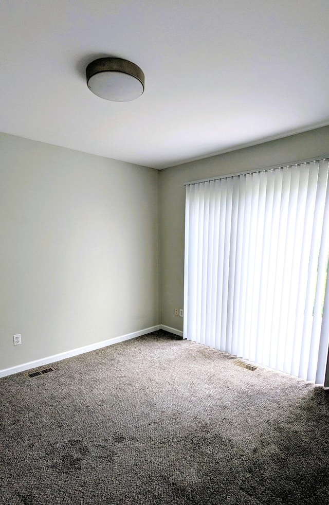spare room featuring carpet flooring and baseboards