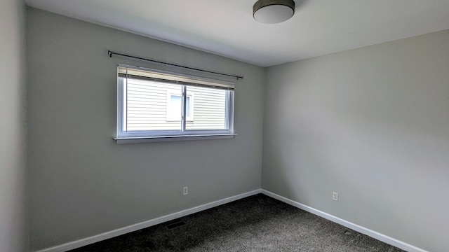 spare room featuring baseboards and dark carpet