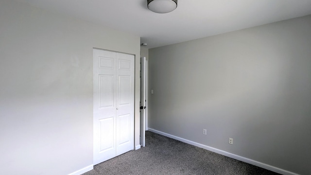 empty room with dark carpet and baseboards