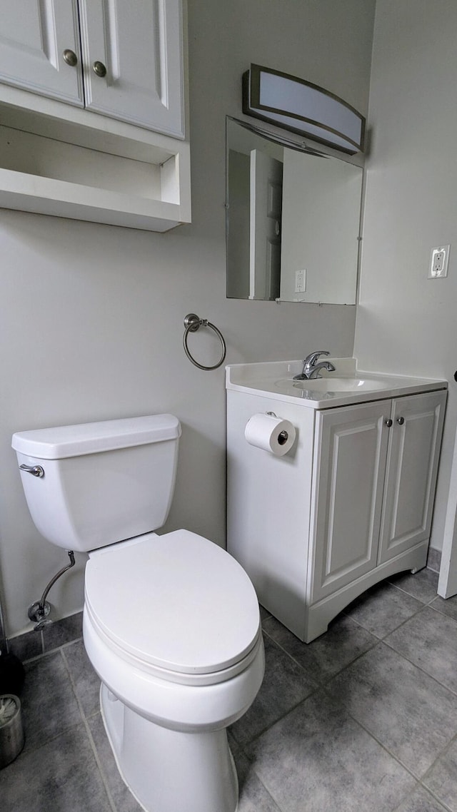 bathroom with toilet, vanity, and tile patterned floors