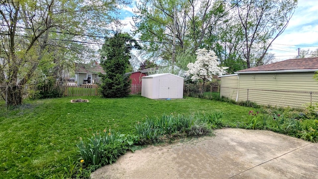 view of yard featuring a storage shed, an outdoor structure, a patio area, and a fire pit