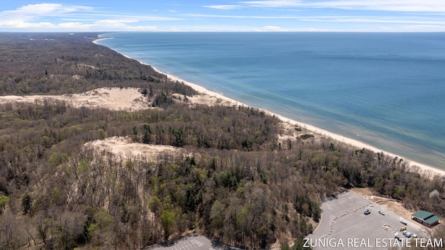 bird's eye view of waterfront with a beach and a heavily wooded area