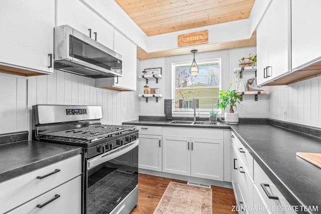 kitchen with stainless steel appliances, a sink, wooden ceiling, dark countertops, and dark wood finished floors