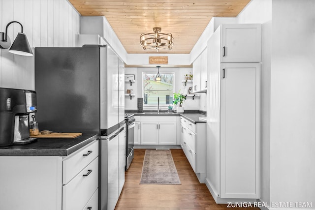 kitchen with stainless steel appliances, dark countertops, wood finished floors, wooden ceiling, and white cabinets