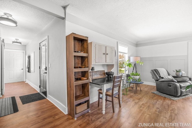 home office featuring a textured ceiling, light wood finished floors, and baseboards