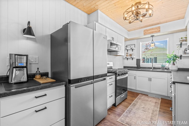 kitchen with appliances with stainless steel finishes, wooden ceiling, dark countertops, a sink, and open shelves