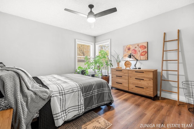 bedroom featuring wood finished floors, ceiling fan, a textured ceiling, and baseboards