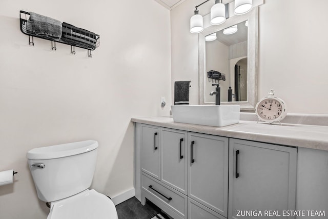 bathroom featuring toilet, vanity, baseboards, and crown molding
