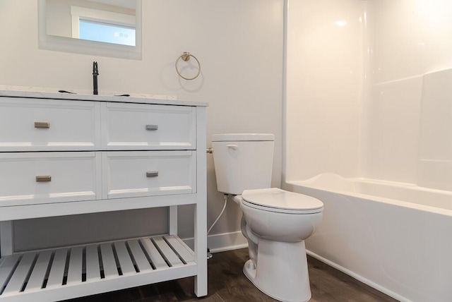 bathroom with wood finished floors, toilet, baseboards, vanity, and  shower combination