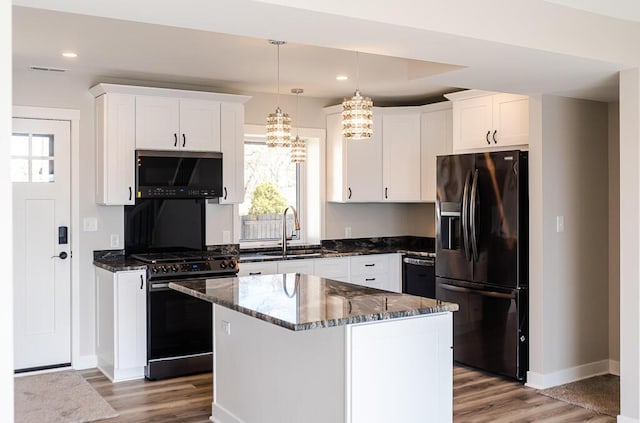 kitchen featuring black appliances, a sink, a chandelier, baseboards, and light wood-type flooring