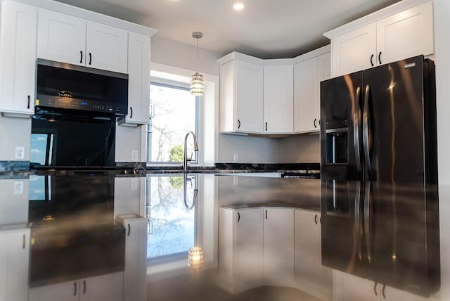 kitchen featuring black refrigerator with ice dispenser, white cabinetry, pendant lighting, recessed lighting, and a sink