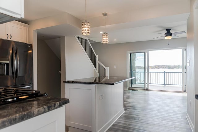 kitchen featuring black fridge, wood finished floors, white cabinetry, ceiling fan, and decorative light fixtures