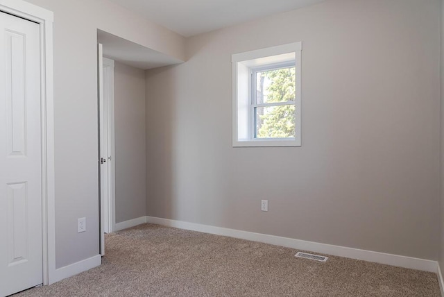 unfurnished room featuring light carpet and baseboards