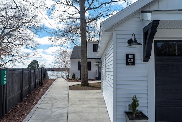 view of home's exterior with fence, roof with shingles, and board and batten siding