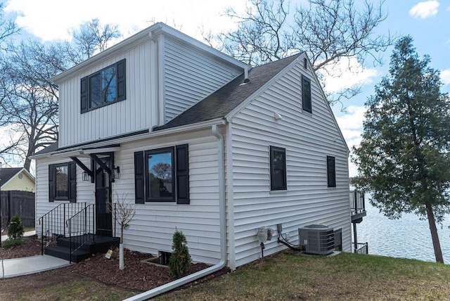 view of home's exterior featuring cooling unit, fence, a shingled roof, and board and batten siding