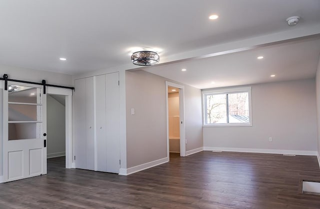 empty room with a barn door, baseboards, dark wood-type flooring, a smoke detector, and recessed lighting