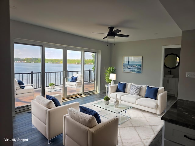 living room with a water view, wood finished floors, and ceiling fan