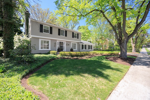 colonial home with a chimney and a front yard