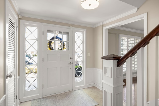entrance foyer with plenty of natural light, light tile patterned flooring, ornamental molding, wainscoting, and a decorative wall