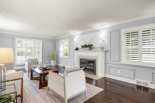 living room featuring a decorative wall, a fireplace, crown molding, and wood finished floors