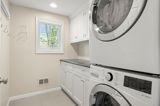 laundry room featuring stacked washer and clothes dryer, cabinet space, baseboards, and recessed lighting