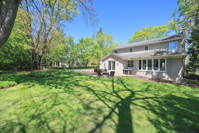 back of house with brick siding, a patio, a chimney, and a yard