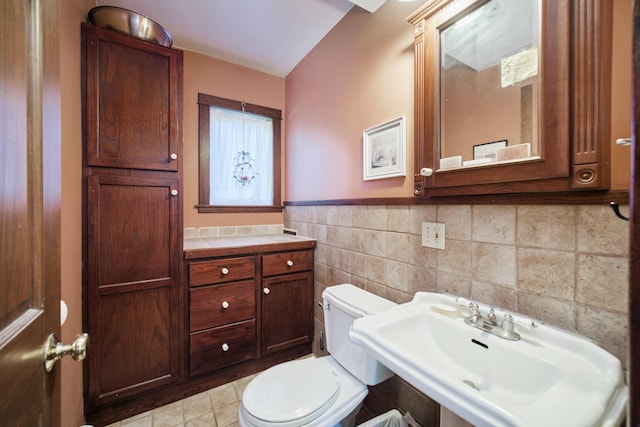 1621 W Beyer Rd, Ludington, MI 49431 - half bathroom with a sink, tile walls, toilet, a wainscoted wall, and tile patterned flooring