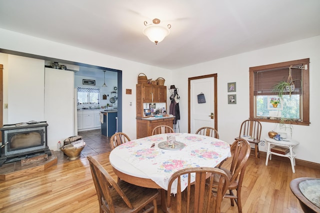 1621 W Beyer Rd, Ludington, MI 49431 - dining area featuring a wood stove, light wood-style flooring, and baseboards