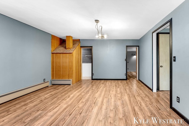 405 S 1st St, Edmore, MI 48829 - unfurnished living room featuring a baseboard heating unit, light wood finished floors, baseboards, and a chandelier