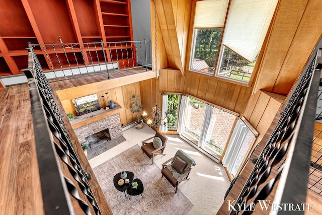 405 S 1st St, Edmore, MI 48829 - living room featuring plenty of natural light, wood walls, a baseboard heating unit, a brick fireplace, and wood finished floors
