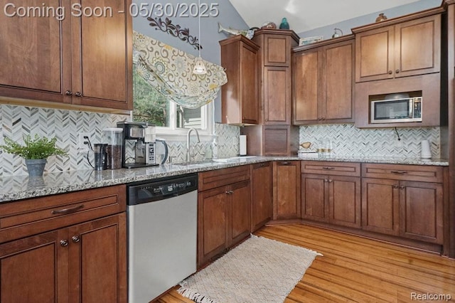 9450 Sandlewood Ct, Whitmore Lake, MI 48189 - kitchen with stainless steel appliances, a sink, brown cabinets, light stone countertops, and light wood-style flooring