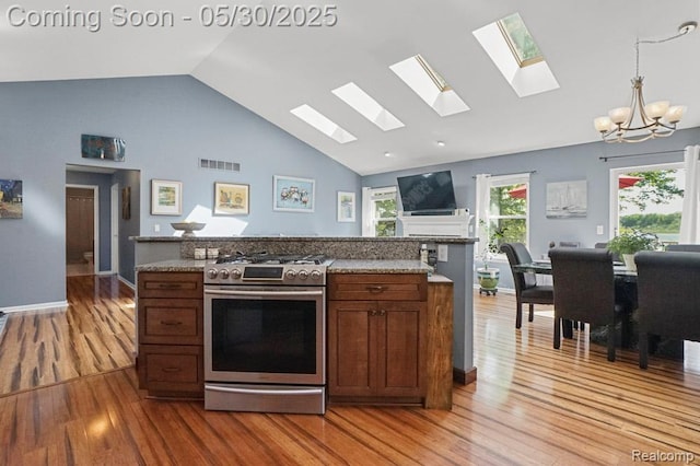 9450 Sandlewood Ct, Whitmore Lake, MI 48189 - kitchen with stainless steel range with gas cooktop, a skylight, light wood-style flooring, a chandelier, and high vaulted ceiling