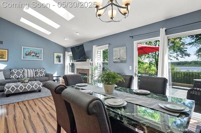 9450 Sandlewood Ct, Whitmore Lake, MI 48189 - dining space featuring lofted ceiling, a chandelier, a glass covered fireplace, a skylight, and wood finished floors