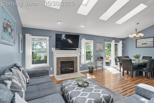 9450 Sandlewood Ct, Whitmore Lake, MI 48189 - living area featuring a chandelier, vaulted ceiling, a skylight, a fireplace, and wood finished floors