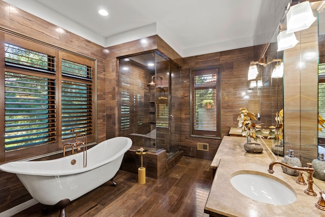bathroom with a freestanding bath, wood finished floors, vanity, wood walls, and walk in shower