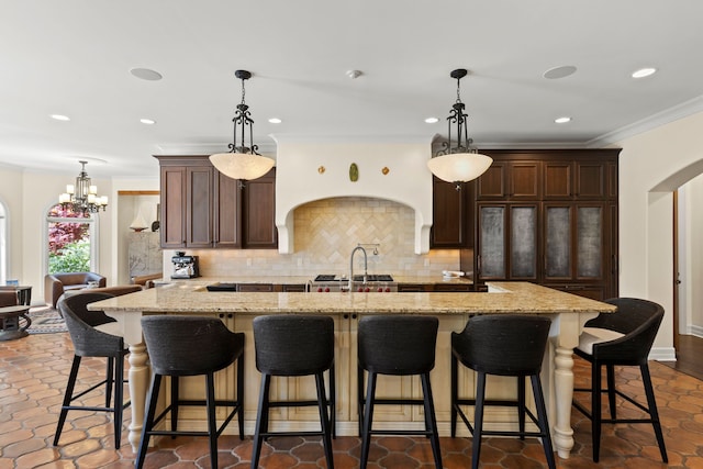 kitchen with tasteful backsplash, arched walkways, dark brown cabinetry, a chandelier, and recessed lighting