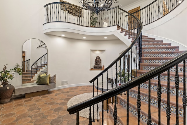 stairway featuring a high ceiling, stone finish floors, a chandelier, recessed lighting, and baseboards