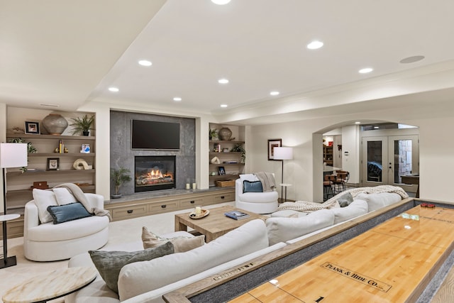 living room with arched walkways, built in features, ornamental molding, recessed lighting, and a high end fireplace