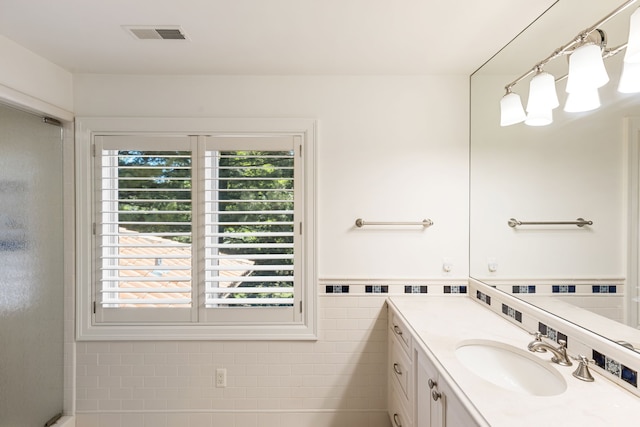 full bath featuring plenty of natural light, vanity, tile walls, and a wainscoted wall