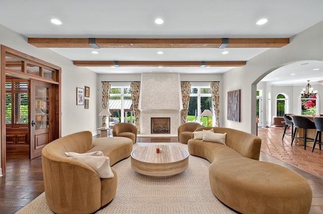 living area featuring arched walkways, recessed lighting, beamed ceiling, healthy amount of natural light, and a large fireplace