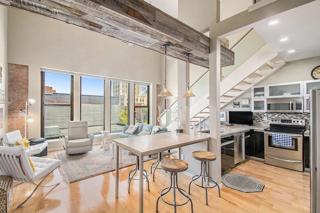 101 W Liberty St Unit 320, Ann Arbor, MI 48104 - kitchen with stainless steel appliances, a high ceiling, light wood-type flooring, glass insert cabinets, and tasteful backsplash